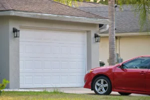A red car parked in front of a garage